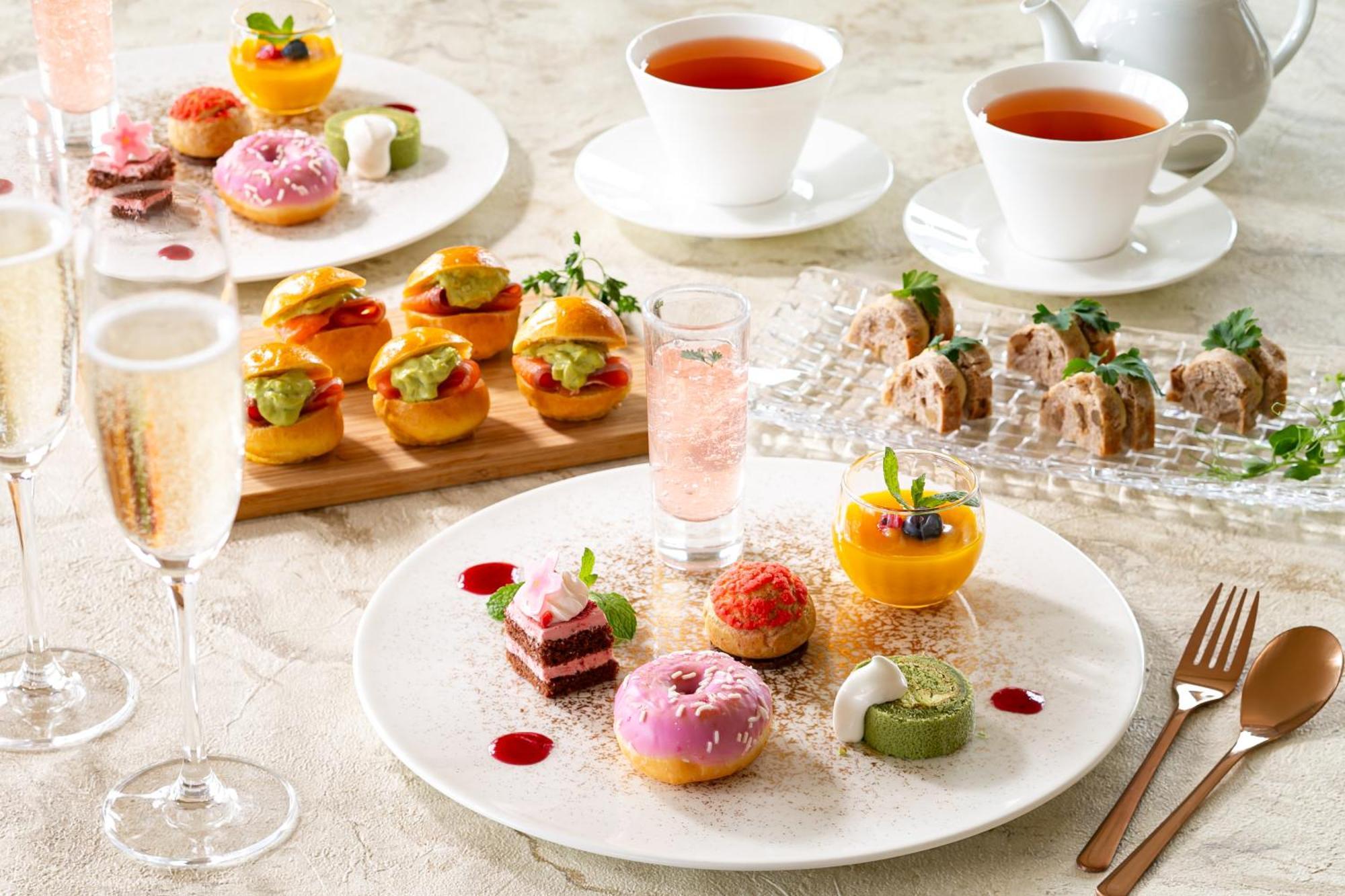 神戸メリケンパークオリエンタルホテル 神戸市 エクステリア 写真 The photo features an elegant afternoon tea setup. There are two cups of tea and a teapot on the table, accompanied by various beautifully arranged desserts and pastries. 

On one plate, there are colorful treats including small cakes, doughnuts with